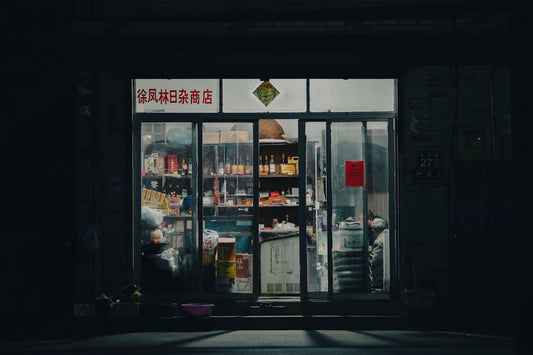 A dark street with a store front lit up at night