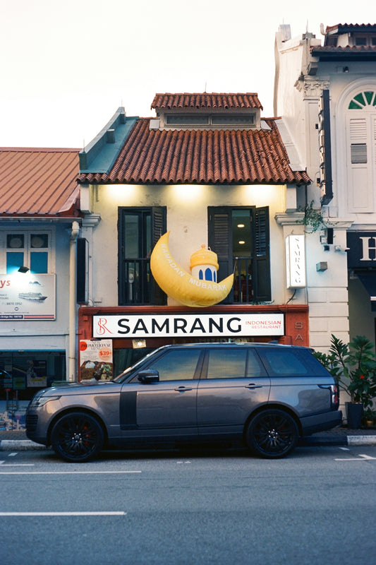 A luxury car parks in front of a shop.